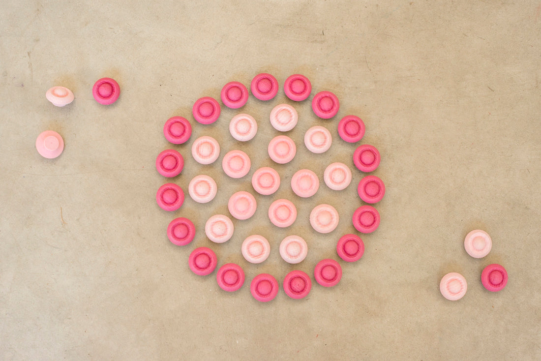Wooden circle mandala pieces in various shades of pink are arranged in a circle pattern they are grouped by shade.