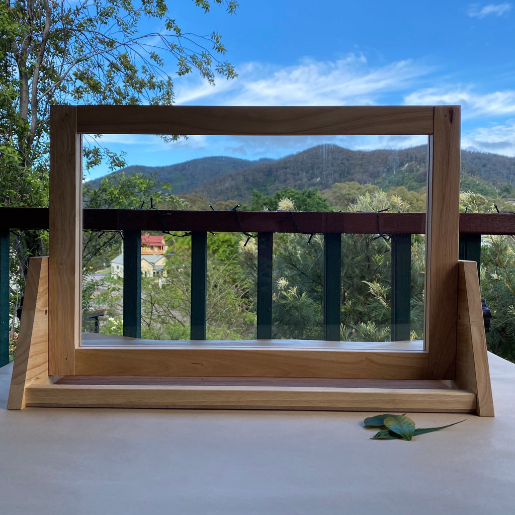 Wooden framed desktop perspex easel with mountain view in background